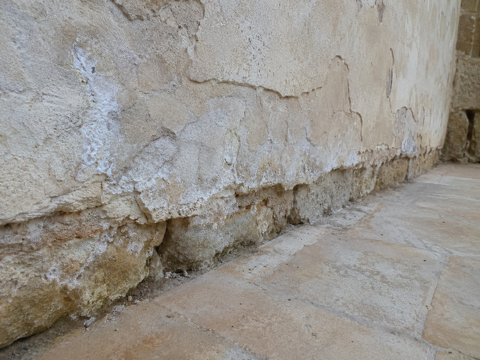 Mur ancien avec enduit décollé et traces d’humidité